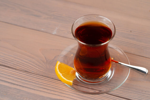盘子木桌上放着一杯土耳其茶和一片柠檬土耳其茶传统茶土耳其茶