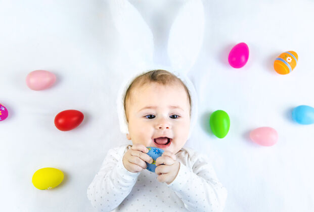 童年宝宝穿得像兔子 在白色的表面上放复活节彩蛋人婴儿表情