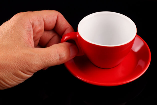 干净手拿着一个空的红色杯子和一个放在黑色表面上的碟子餐具器皿闪亮