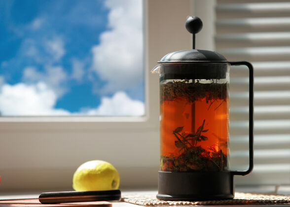 窗户窗户上的玻璃茶壶里放着异国情调的鲜花绿茶热健康输液