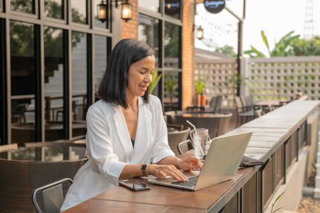 女士女商人在咖啡馆用笔记本电脑的画像女商人坐着街道