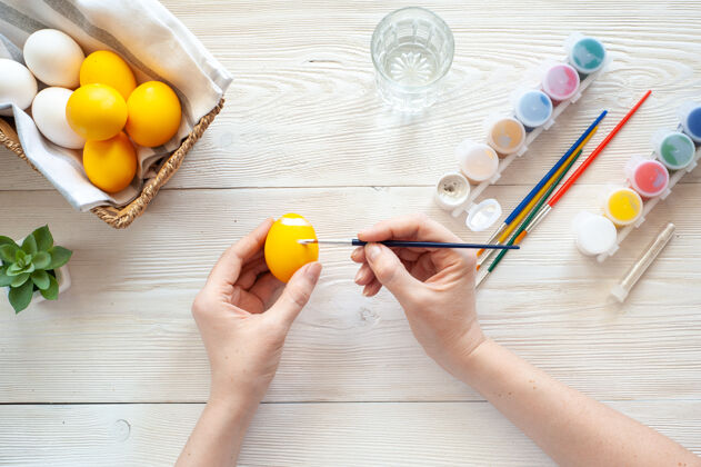 绘画给鸡蛋着色那个女孩在黄色的鸡蛋上画银色的图案画笔画笔彩色