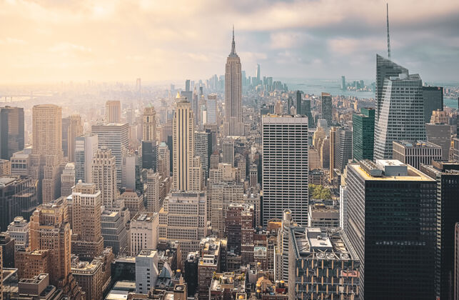 州在阳光明媚的日子里俯瞰纽约城的标志性景观摩天大楼之间的阳光和多云的背景旅游概念纽约 美国美国城市灯光