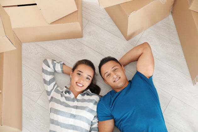 女人幸福的年轻夫妇躺在地板上在他们的新公寓附近移动箱子谎言搬家不动产