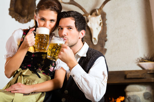 浪漫一对夫妇在一个传统的山间小屋与壁炉喝啤酒火客厅啤酒