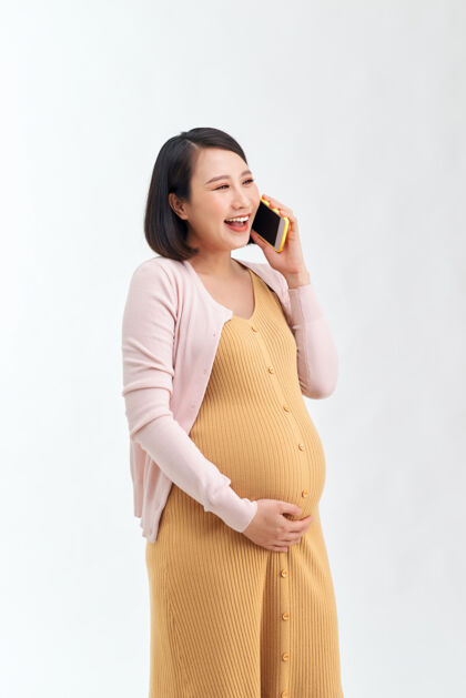 孕妇快乐的孕妇在家打电话给智能手机女性肚子肚子