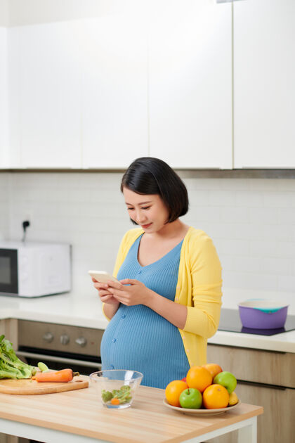 通讯快乐的孕妇使用智能手机上的语音命令录音机怀孕亚洲人期望
