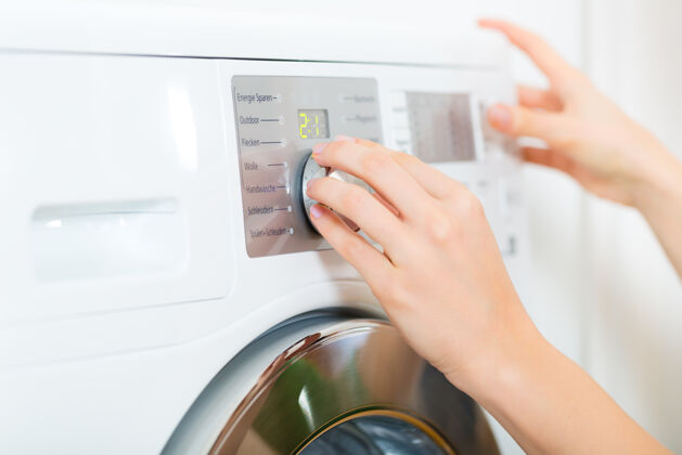 洗衣机年轻女子或管家有一天在家洗衣 她选择的程序家务家政烘干机