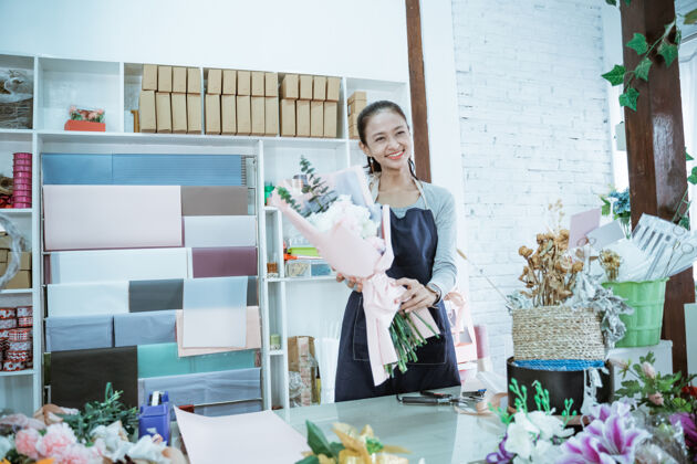 束快乐的年轻女子花店工作的花店持有法兰绒花期待前方准备拿起围裙订单室内