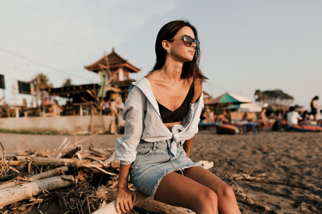 沙滩可爱可爱的女孩 深色短发 裙子 蓝色衬衫 阳光下坐在沙滩上白种人地平线沙滩