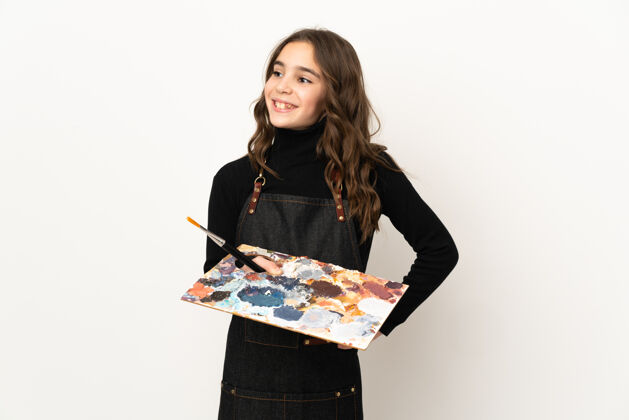 艺术一个小艺术家女人拿着一个调色板孤立地站在白墙上摆姿势 双臂放在臀部 微笑着小积极微笑