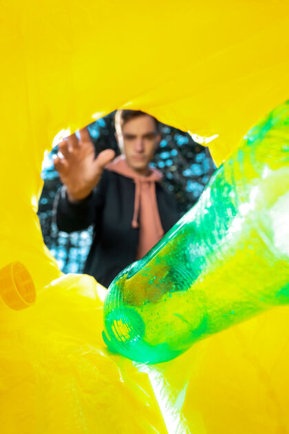 人把一个绿色塑料瓶扔进垃圾桶的人垃圾盒子保护