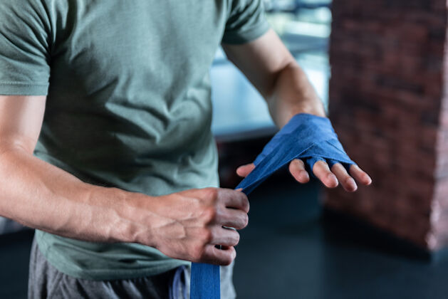 比赛强壮的手特写运动员的强壮的手在体育馆训练使用长的蓝色手腕包裹课运动健身房