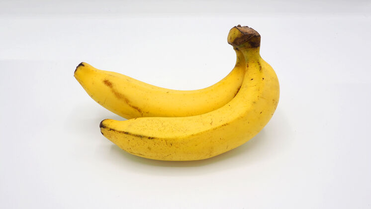果肉白色桌子上有两个真正的黄色香蕉果束果皮香蕉