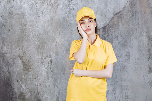 工人身着黄色制服的女服务人员站在水泥墙上 神情迷茫 若有所思苍白聪明晋升