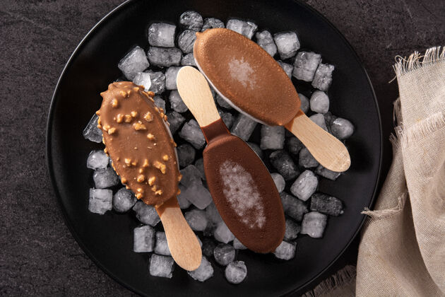 夏天巧克力冰棒和碎冰放在黑桌子上有机冷藏盘子
