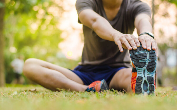 慢跑特写年轻男子跑步者热身和伸展训练前在日落时间自然健身活动