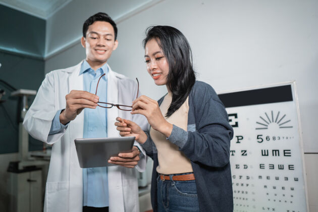 帮助一位男医生正在给女病人分析结果 并在眼科诊所检查后出示推荐的眼镜亚洲人处方咨询