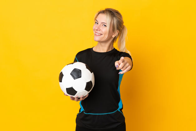 年轻年轻的俄罗斯足球运动员 一个被隔离在黄色背景下的女人 带着快乐的表情指着前面女子指向比赛