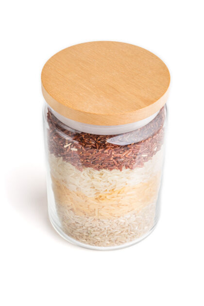 配料玻璃缸里盛着不同种类的大米 层层地倒在白色的表面上接近罐子厨房