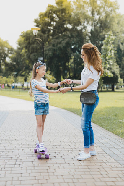 童年休闲时间时尚美丽的妈妈和她的女孩在美丽的绿色公园里度过她的休闲时间跑步微笑养育