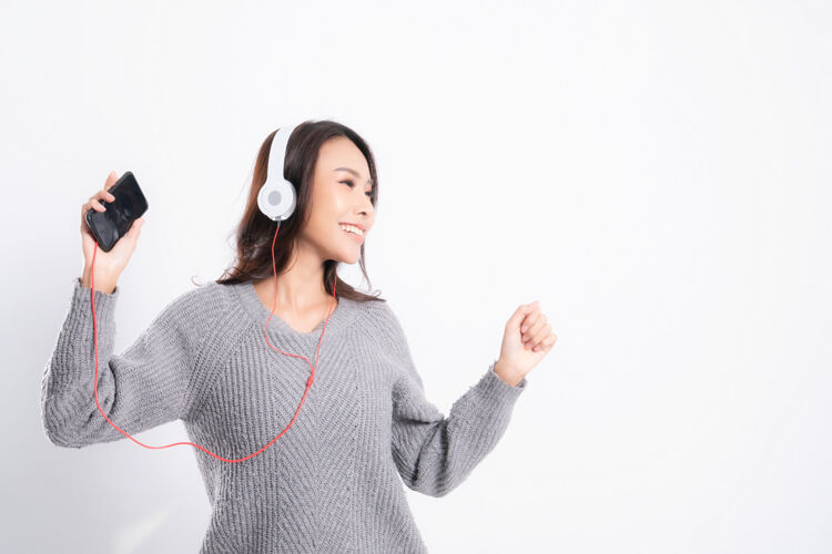 播放美丽的亚洲女人戴着耳机听音乐耳机舒适娱乐