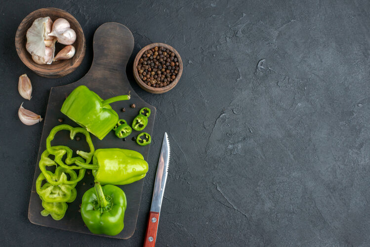 整个全切切碎的青椒在黑色表面右侧深色木砧板上的特写镜头沙拉甜椒板