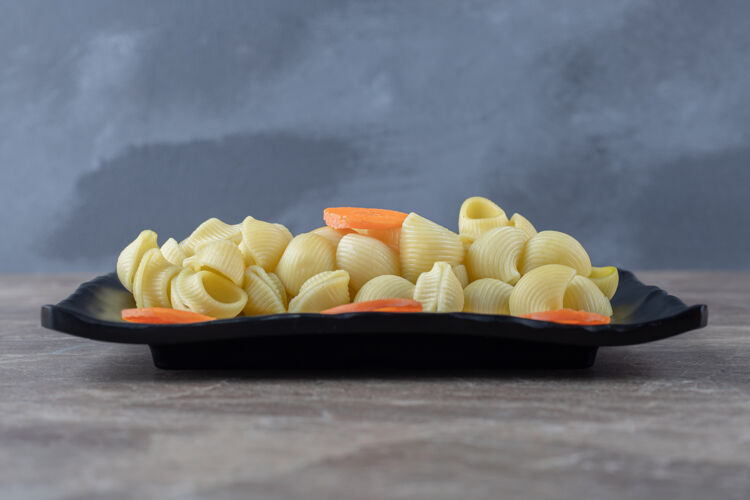 美味美味的胡萝卜片放在意大利面旁边 放在木盘上 大理石表面美味胡萝卜营养