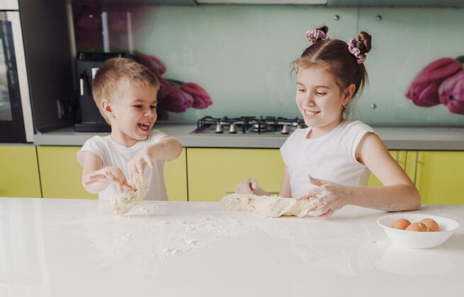 混乱漂亮的男孩和女孩在厨房里伸展面团 一边玩耍一边玩耍cooking.happy快乐的孩子们女孩烘焙室内