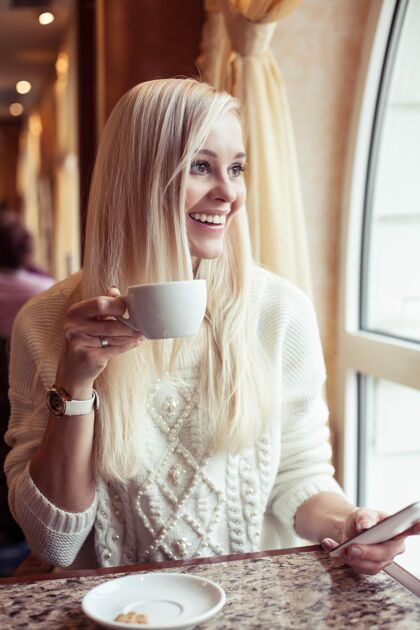 咖啡馆女人的手拿着一杯热可可一个年轻的女人坐在一个舒适的房间里咖啡馆女孩在喝酒可可冬天舒适秋天热的吸管勺子