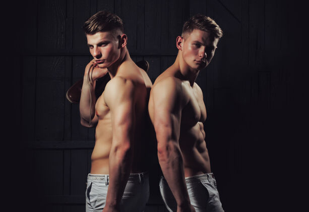 男两个年轻的男性双胞胎 性感的身体展示了他们肌肉发达的躯干和腹肌运动员肌肉健身