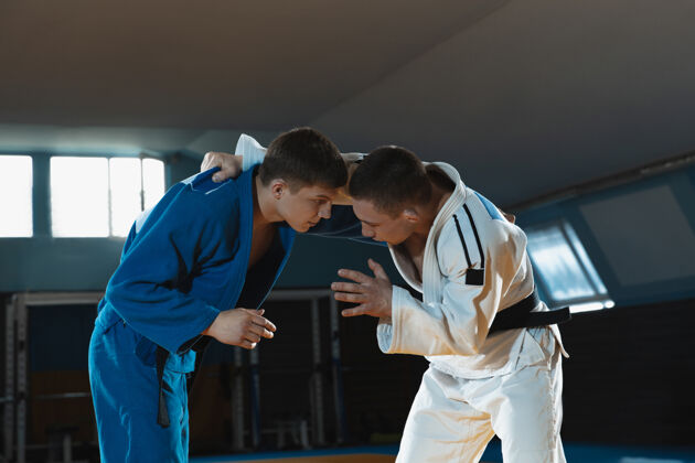 力量两个穿着和服的年轻柔道选手在体育馆里练习武术战斗比赛练习