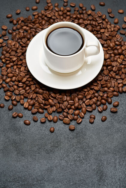 热的在水泥桌上烤咖啡豆上放一杯浓咖啡配料烤杯子