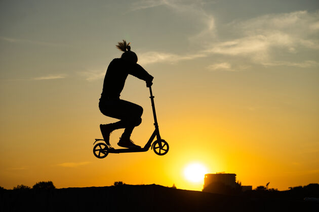 年轻人一个男人骑着脚踏车和美丽的日出跳跃的剪影技巧男性运动