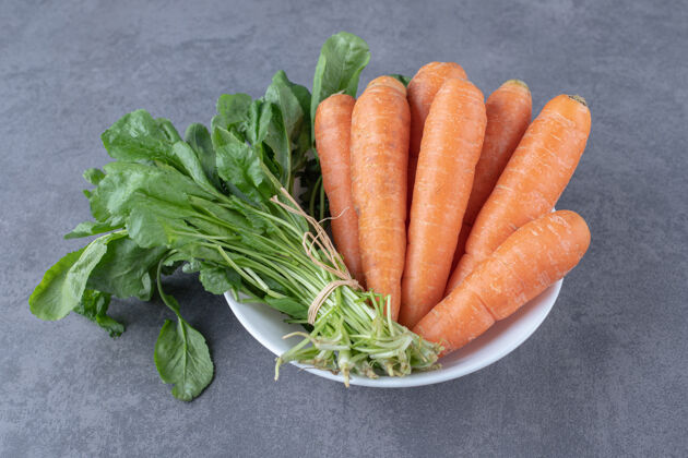 美味绿色蔬菜和胡萝卜放在碗里 放在大理石表面上美味绿色胡萝卜