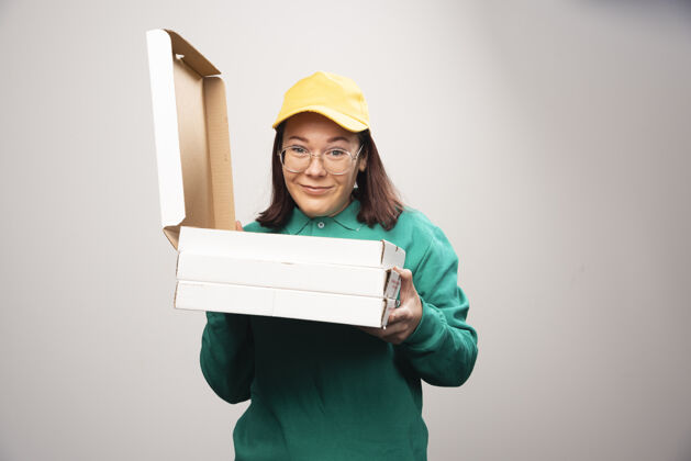 香气女送货员拿着一张白色的高质量的比萨饼卡片帽子模型制服
