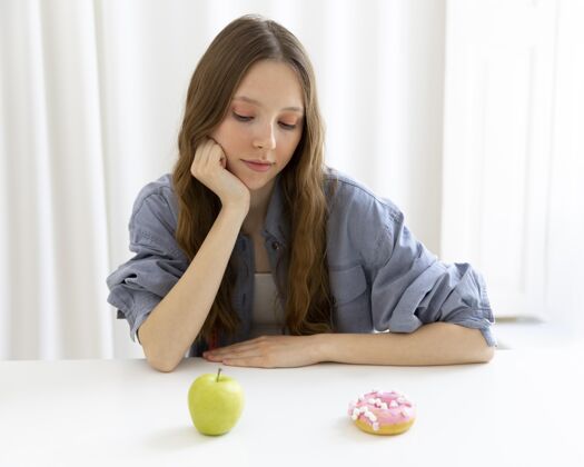 保健看甜甜圈和苹果的女人饮食模特生活方式