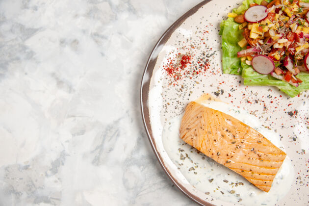 鱼粉近距离观看鱼粉和美味沙拉在一个盘子上染色白色表面与自由空间污渍午餐一餐