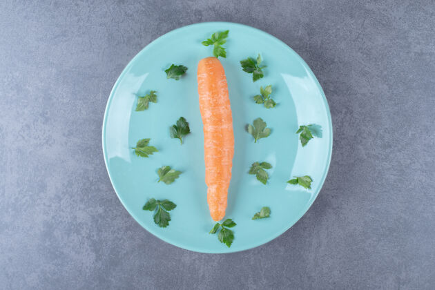 农业一根胡萝卜放在盘子里 上面是绿色的 放在大理石表面上盘子蔬菜风味