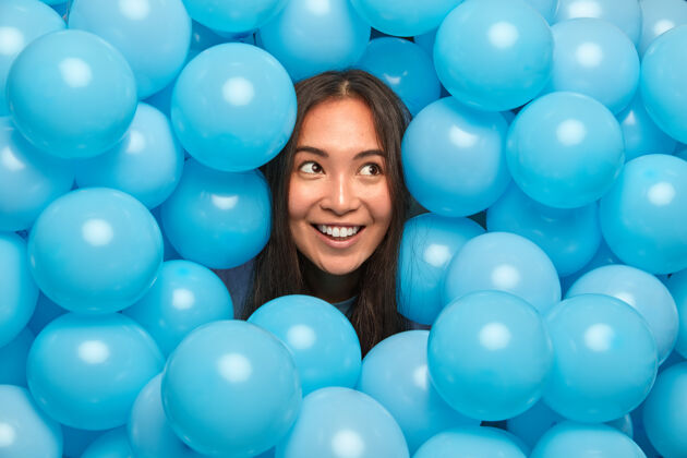满意一位深色头发的女士享受着节日庆典 她若有所思地看着身边被许多膨胀的蓝色气球包围着喜悦思想头