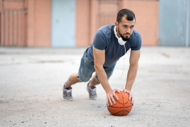 篮街上有个男人靠在篮球上做俯卧撑比赛人活跃