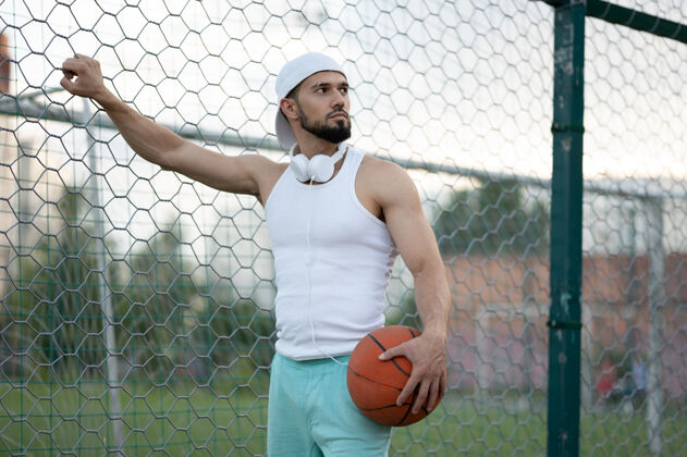 户外一个男人站在街上的栅栏旁 手里拿着一个篮球人篮球训练