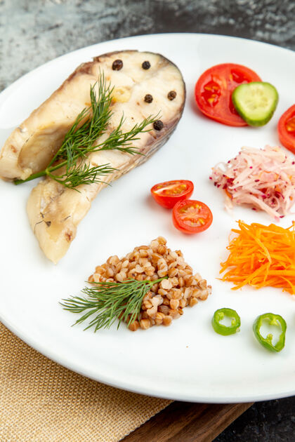 高高分辨率的照片煮鱼荞麦饭与蔬菜绿色在一个白色的盘子上裸体毛巾木砧板在冰面上裸体晚餐毛巾