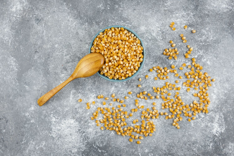 天然用木勺把生玉米粒放在蓝碗里生的种子玉米