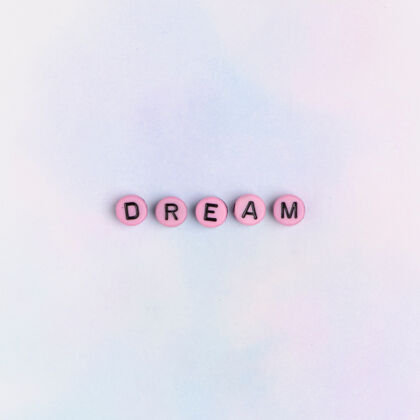 积极梦幻单词珠子文字排版在桌子上粉色珠子大写字母动机