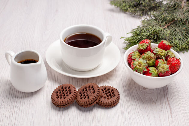 杯子前视一杯茶加饼干和草莓放在白桌子上糖茶饼干饼干甜糖浓缩咖啡早餐