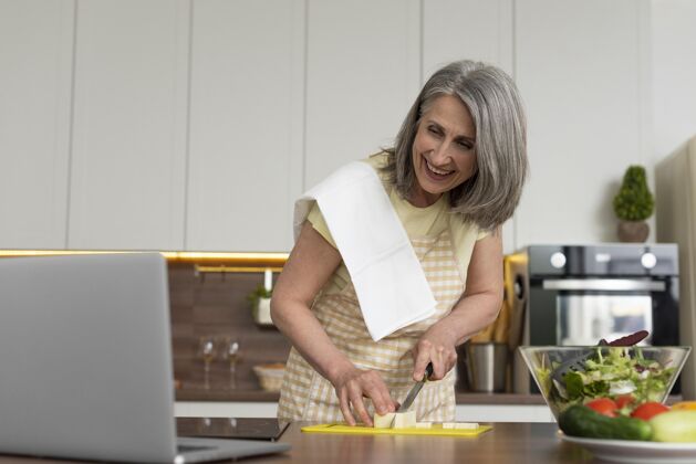 女人家里的老太太在厨房用笔记本电脑上烹饪课笔记本电脑内部学习