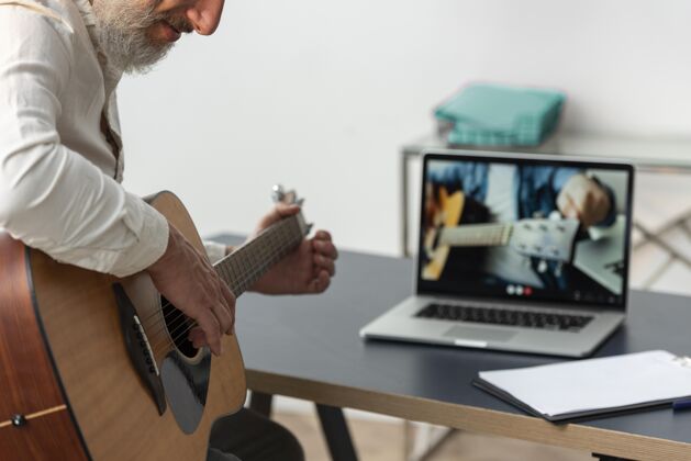 男人在家学习吉他课笔记本电脑的高级男子成人老年人室内