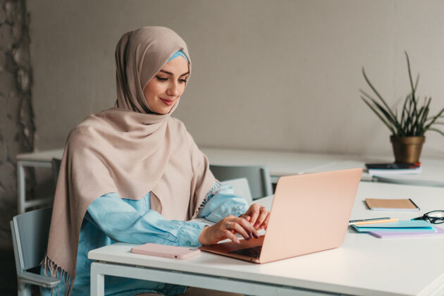 阿拉伯语年轻漂亮的现代妇女戴着头巾在办公室的笔记本电脑上工作 教育在线办公桌互联网围巾