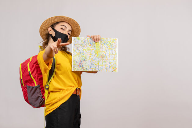 人正面图年轻的旅行者背着背包举着地图指向前方灰色旅游面具